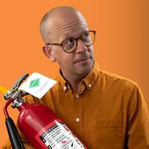 Kevan holding a red fire extinguisher, glancing up and away